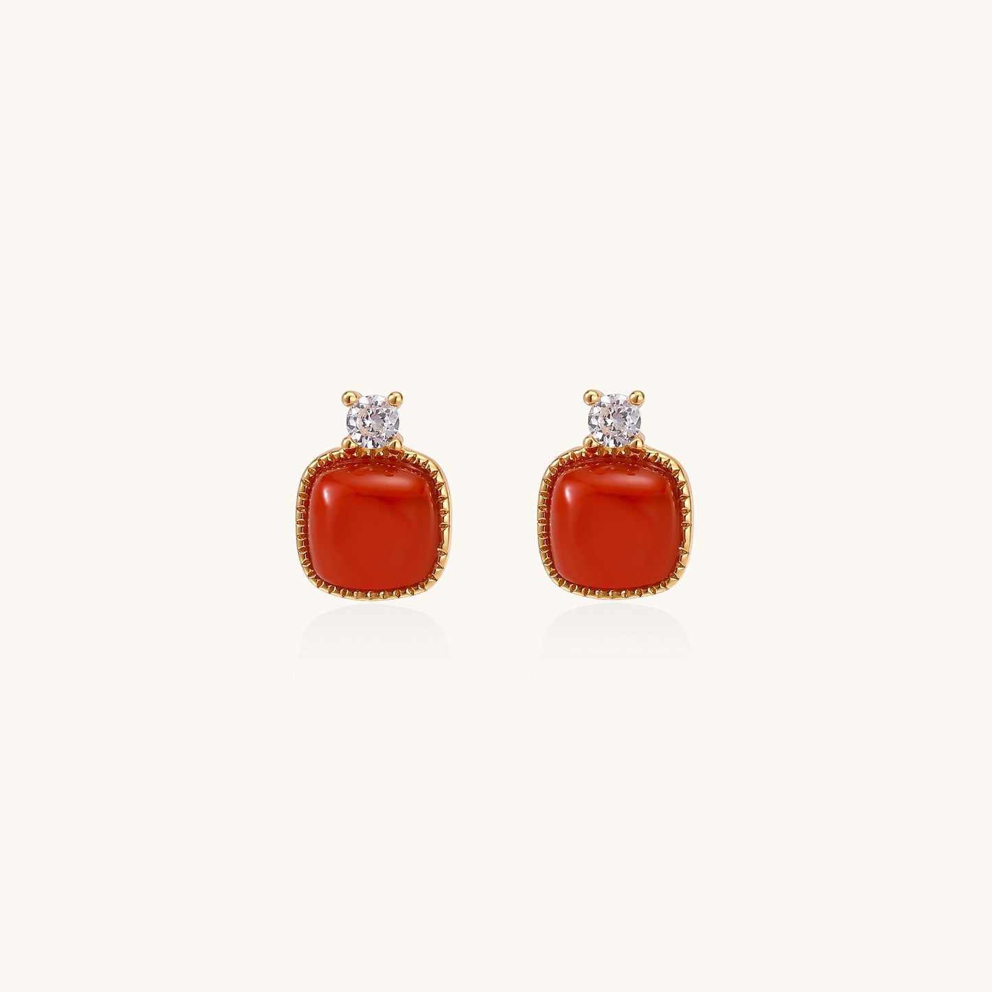Gold-plated sterling silver stud earrings with square south red agate stones and clear crystals on cream background