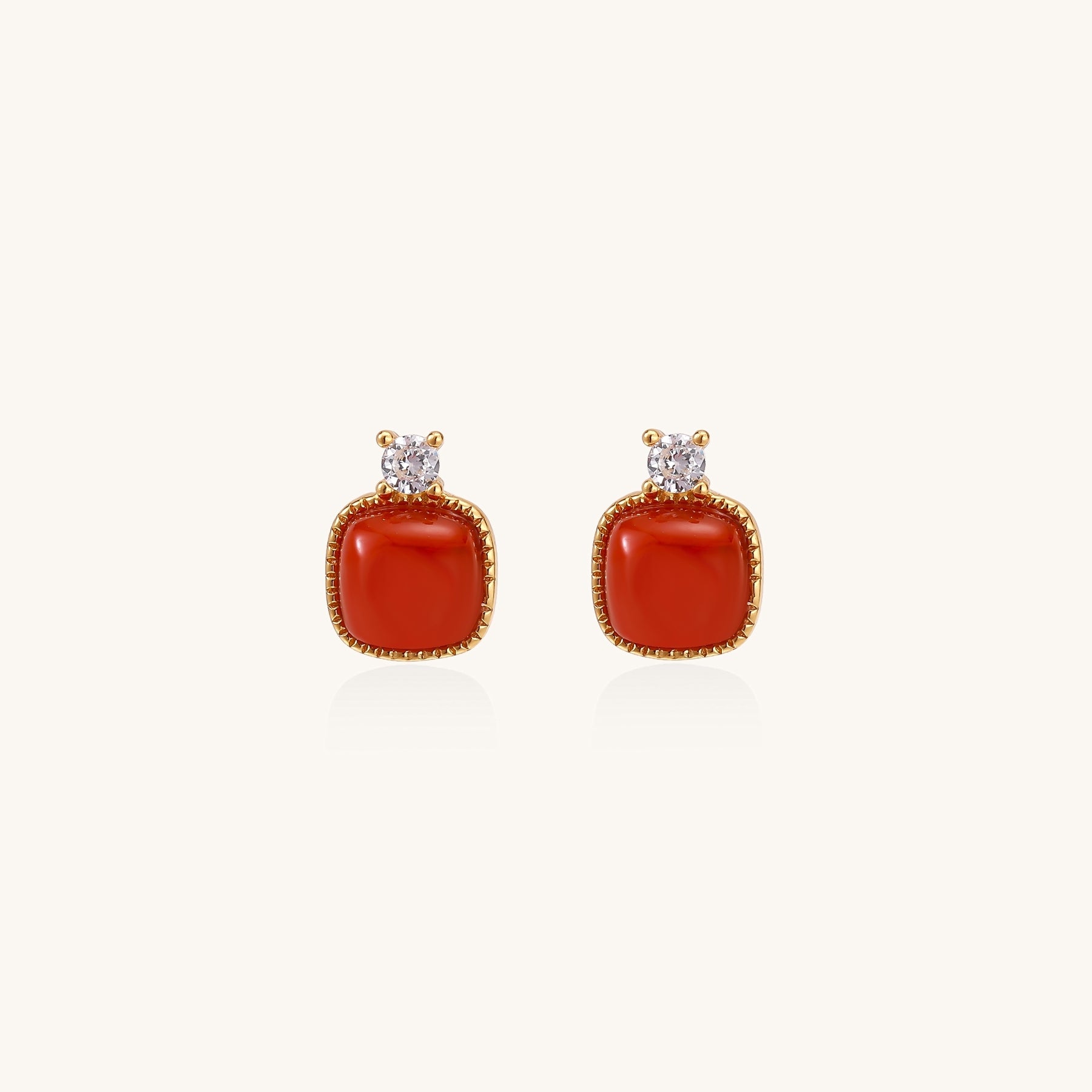 Gold-plated sterling silver stud earrings with square south red agate stones and clear crystals on cream background